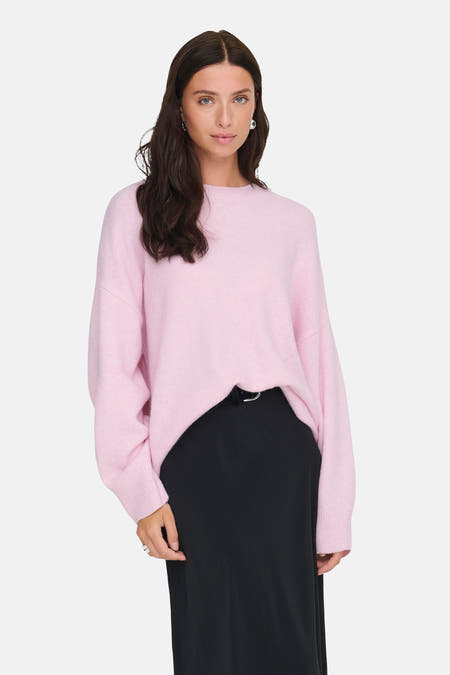Roze trui met ronde hals van JDY, gecombineerd met een zwarte rok en zilveren ringen.