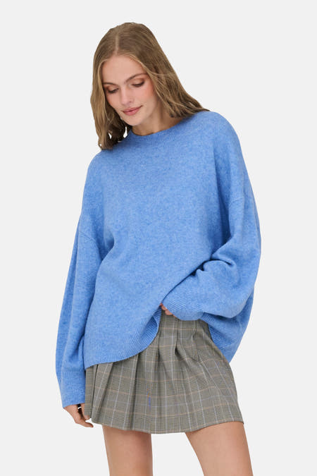 Blauwe trui met ronde hals van JDY, gedragen met een geruite minirok.
