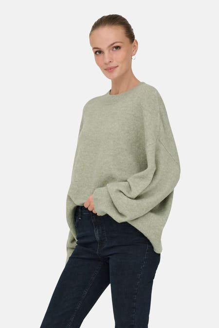 Groene trui met ronde hals van JDY, gedragen met een donkere spijkerbroek en zilveren oorbellen.
