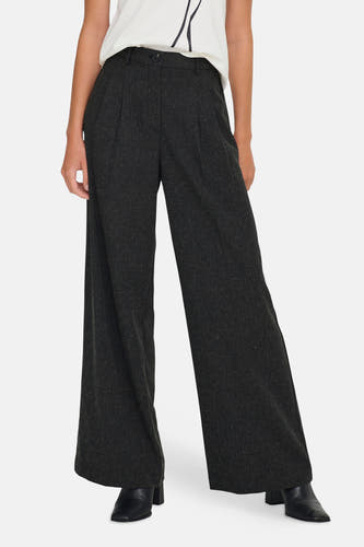 Pantalon gris de JDY, avec des jambes larges et porté avec un T-shirt blanc à une application de fleurs noires.