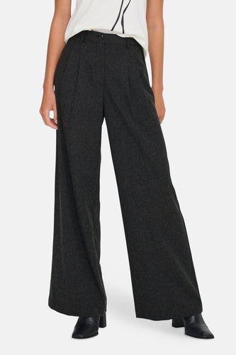 Grijze wijde pantalon met plooien en zwarte laarsjes.
