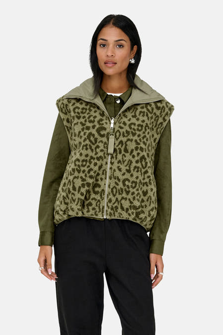 Khaki bodywarmer van ONLY met dierenprint, gedragen over een olijfgroen overhemd en zwarte broek.
