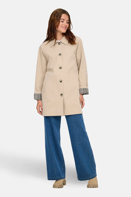 Beige lange jas van ONLY met knoopsluiting, gecombineerd met wijde jeans en grove laarsjes.
