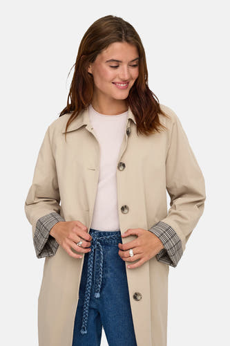 Manteau long beige de ONLY®, avec une encolure dégagée et des jeans bleus boutonnés.