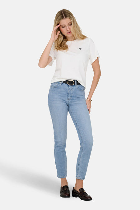 Lichtblauwe denim mom jeans van ONLY, gedragen met een witte T-shirt, zwarte riem en bruine loafers.
