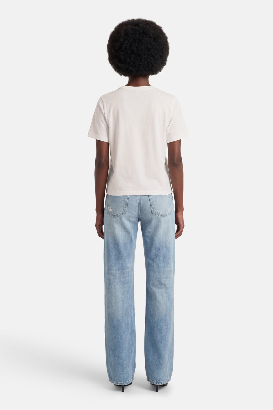 T-shirt blanc à manches courtes ONLY, avec jean décontracté et talons noirs. Vue de dos.