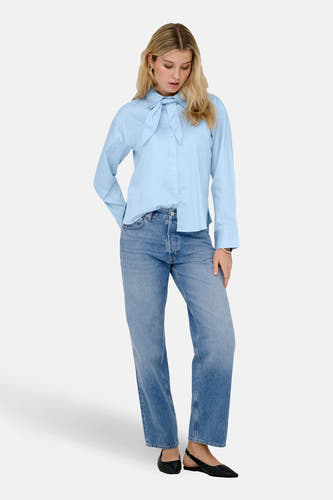 Chemise bleue à manches longues de JDY, avec un détail de nœud et associée à un jean et des chaussures noires.