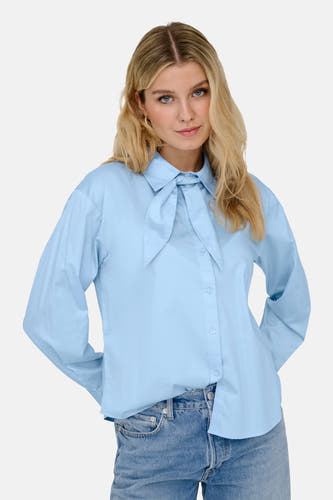 Chemise bleue à manches longues de JDY, avec col à pointes longues et détail noué au col, portée avec un jean.