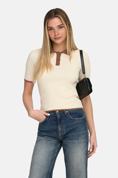 Polo écru à manches courtes de ONLY, avec des bordures marron et porté avec un jean ample et des chaussures noires.