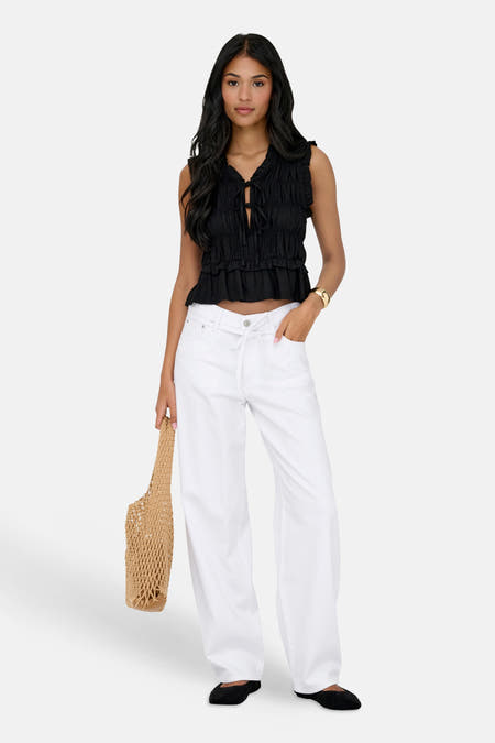 GIANNA witte straight jeans van ONLY, met gekruiste tailleband en een beige nettas.
