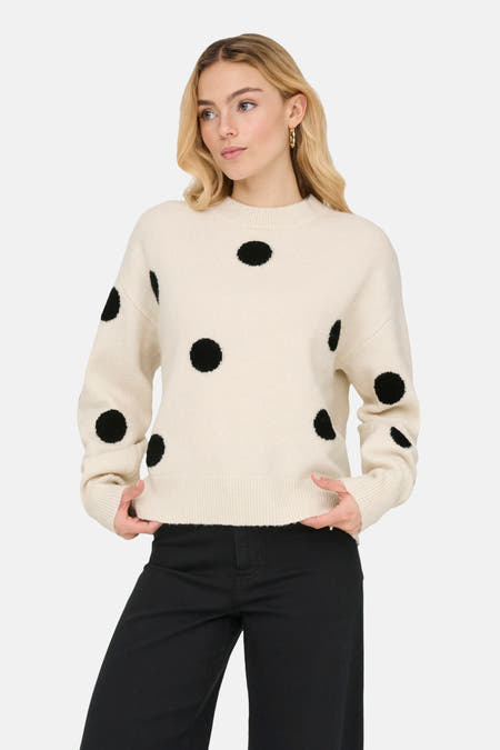 Ecru trui met ronde hals van JDY, met zwarte stippen en gedragen met een zwarte broek.
