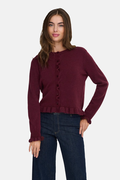 Cardigan Bordeaux de JDY, avec finition froncée et porté avec des jeans foncés et des chaussures marrons.
