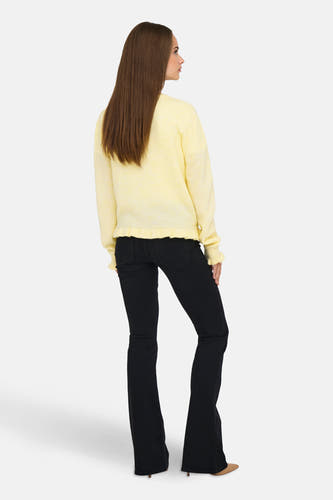 Cardigan jaune de JDY, avec des manches longues et un bord côtelé, associé à des jeans foncés et des baskets.