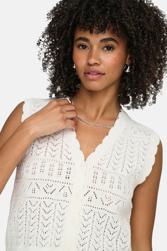 Wit gilet van ONLY® met gehaakt ajourpatroon, geschulpte V-hals en knoopsluiting, gedragen door een model met zilveren ketting.