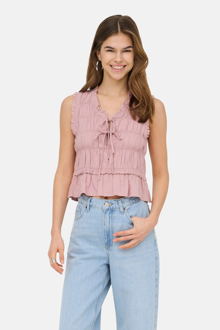 Chemisier sans manches rose de ONLY, avec volants et détail de nœud à l'avant, combiné avec un jean ample.