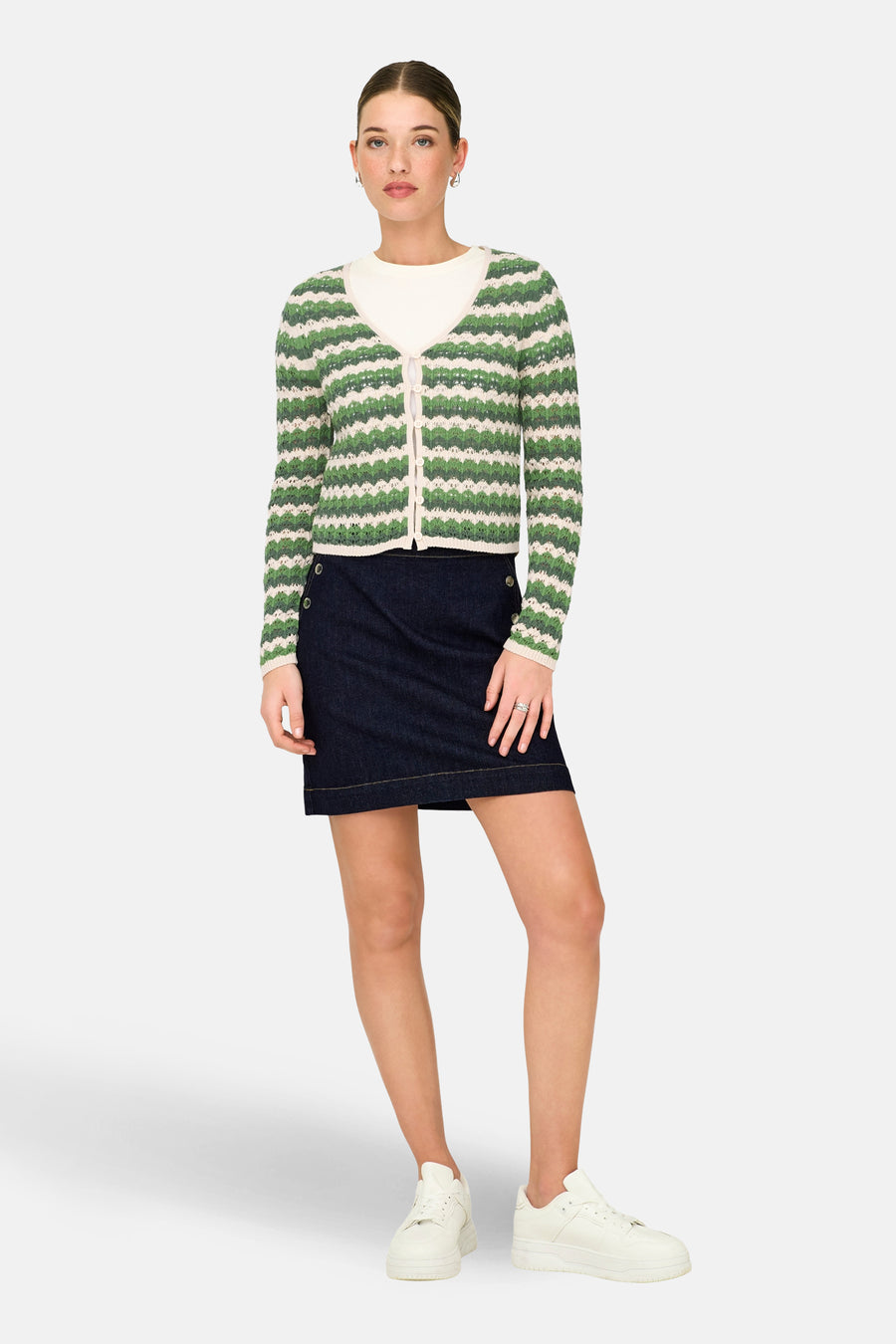 Groene cardigan van ONLY, met crèmekleurige strepen en gedragen over een wit shirt en een donkerblauwe rok.
