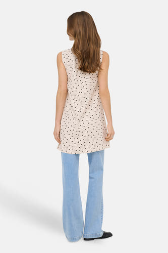 Ecru mouwloos kleedje van ONLY® met zwarte stippen, van achteren gedragen door een model met lichtblauwe flared jeans en zwarte instappers.