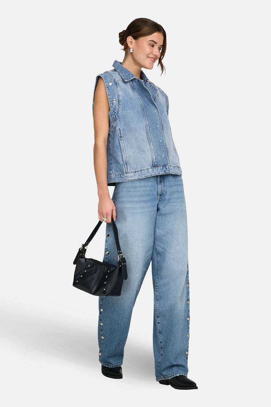 Lichtblauwe rechte jeans van ONLY, met knoopdetails aan de zijkant en gecombineerd met denim vest en zwarte tas.