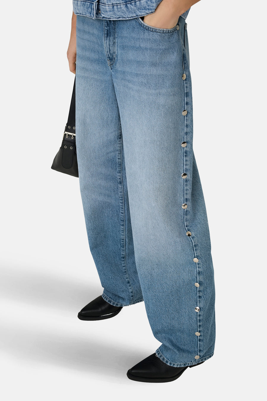 GIANNA lichtblauwe straight jeans van ONLY, met zilverkleurige knopen langs de zijkant en een zwarte handtas.