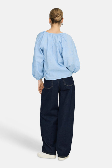 Blauw blouse met lange mouwen van ONLY, met geborduurde details, gecombineerd met een donkerblauwe jeans en witte sneakers.