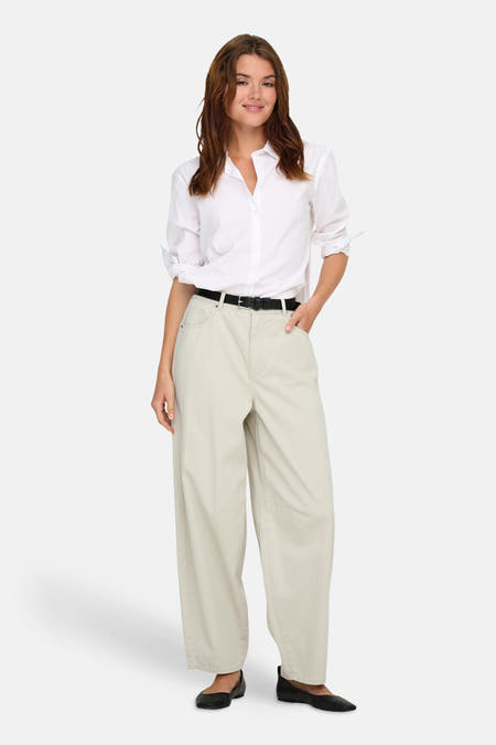 Pantalon écru de ONLY, avec une ceinture noire et des ballerines noires.