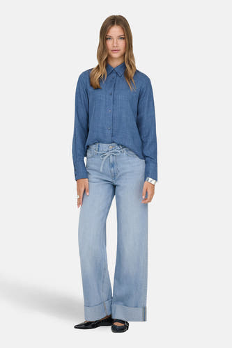 Lichtblauwe denim wide jeans van ONLY, met strikceintuur en opgerolde broekspijpen, gecombineerd met blauw overhemd en zwarte schoenen.
