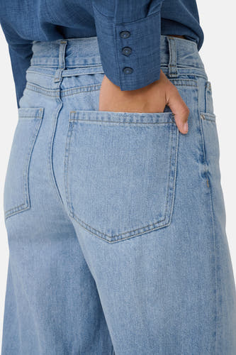 Lichtblauwe denim wide jeans van ONLY, met hand in achterzak en blauw overhemd.

