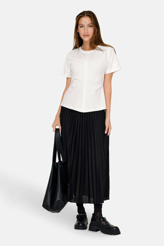 T-shirt blanc à manches courtes de ONLY®, porté avec une jupe plissée noire et un sac noir.