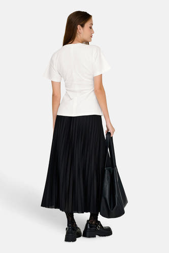 Wit T-shirt met korte mouwen van ONLY®, met geplooide zwarte rok, zwarte laarzen en zwarte tas.
