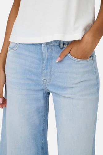 Lichtblauwe flared jeans van ONLY, met steekzak en witte top.
