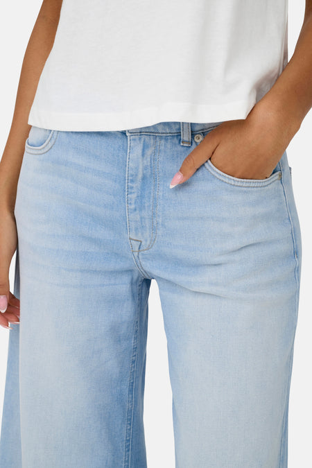 Lichtblauwe flared jeans van ONLY, met steekzak en witte top.
