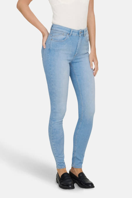 Jean skinny bleu clair ONLY, associé à un top sans manches et des chaussures noires.