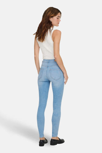 Lichtblauwe skinny jeans van ONLY, met hoge taille en gedragen met een witte top en zwarte loafers.
