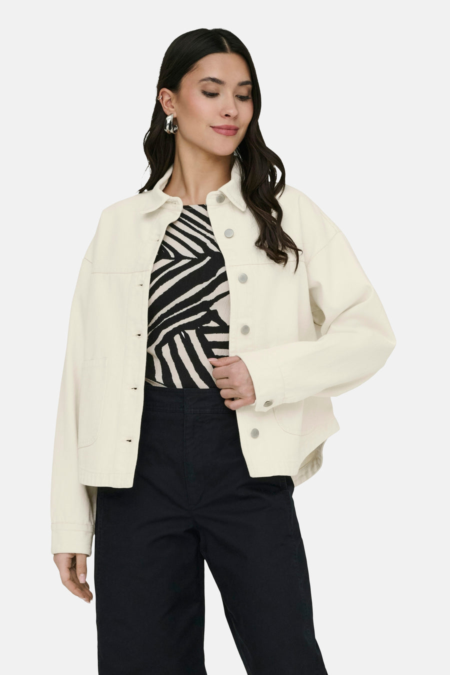 Ecru korte jas van JDY, met lange mouwen, knoopsluiting en gedragen over een zebraprint top en zwarte broek.
