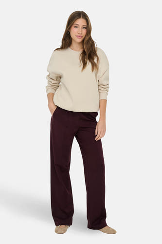 Ecru sweater van ONLY, met lange mouwen, gedragen met bordeauxrode broek en platte schoenen.