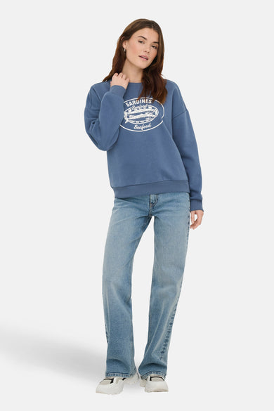 Blauwe sweater met ronde hals van ONLY, met sardientjes-opdruk, gecombineerd met jeans en witte schoenen.