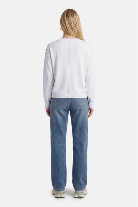 Witte trui met ronde hals van JDY, met roze details langs de schouder en rechte jeans.
