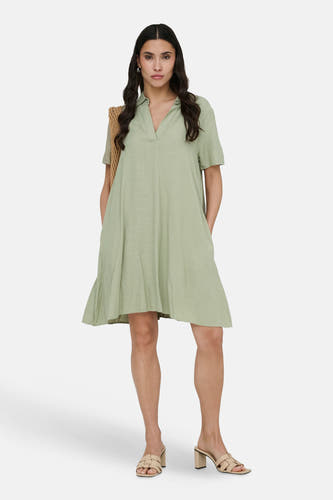 Robe verte à manches courtes de JDY, avec un col en V et un sac au crochet sur l'épaule.