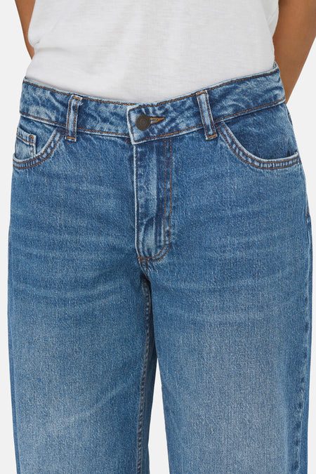 Mid-blauwe wide-leg jeans van JDY met metalen knoop, lichte wassing en een witte top.