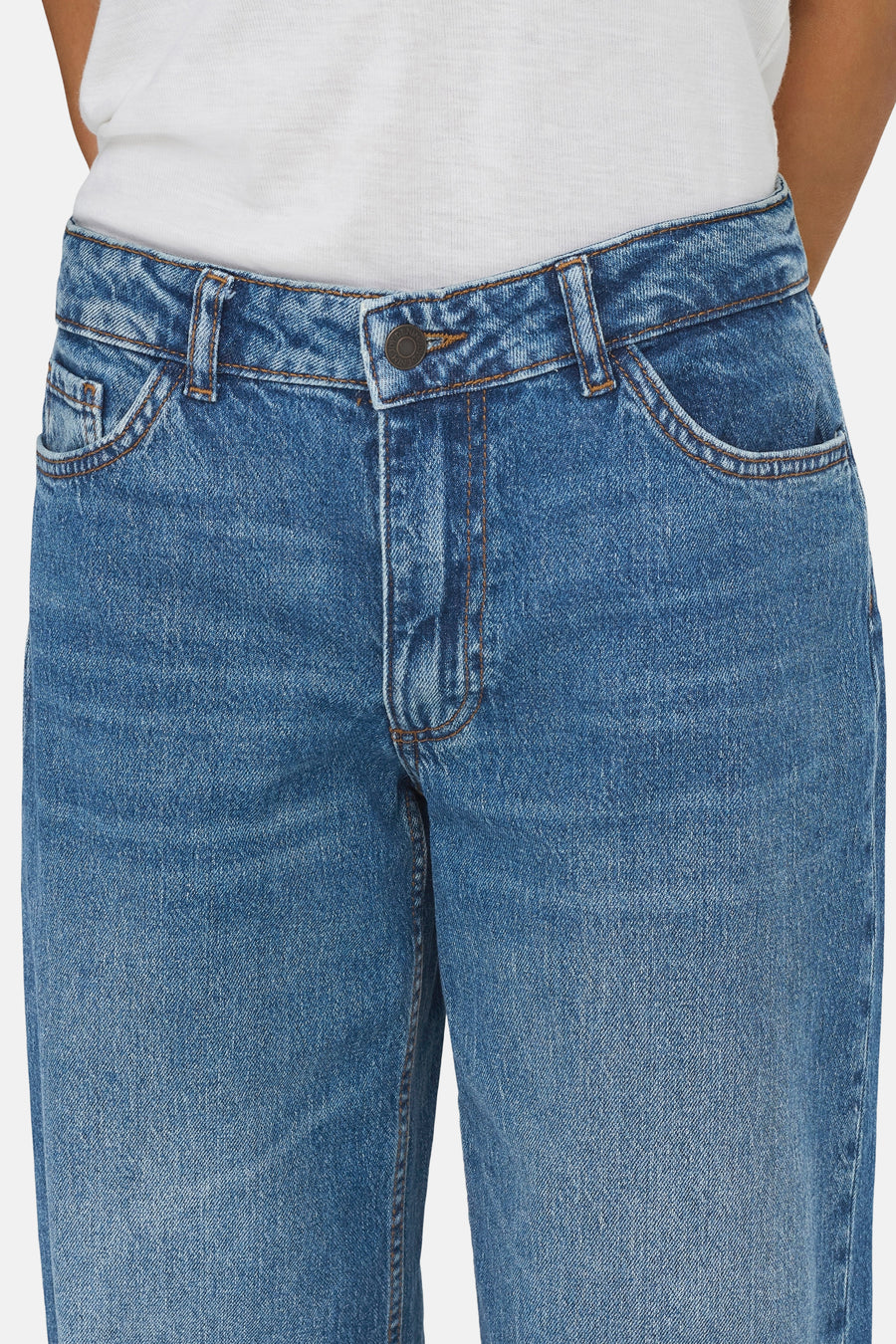 Mid-blauwe wide-leg jeans van JDY met metalen knoop, lichte wassing en een witte top.