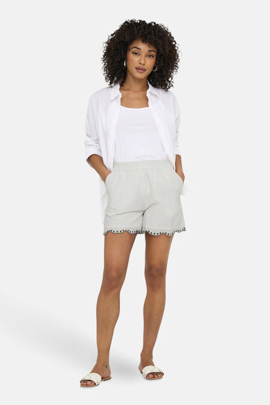 Short blanc de JDY avec une bordure décorative et porté avec un t-shirt blanc et un haut.