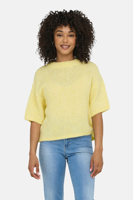 Gele trui met ronde hals van JDY, met korte mouwen en gedragen met blauwe jeans.

