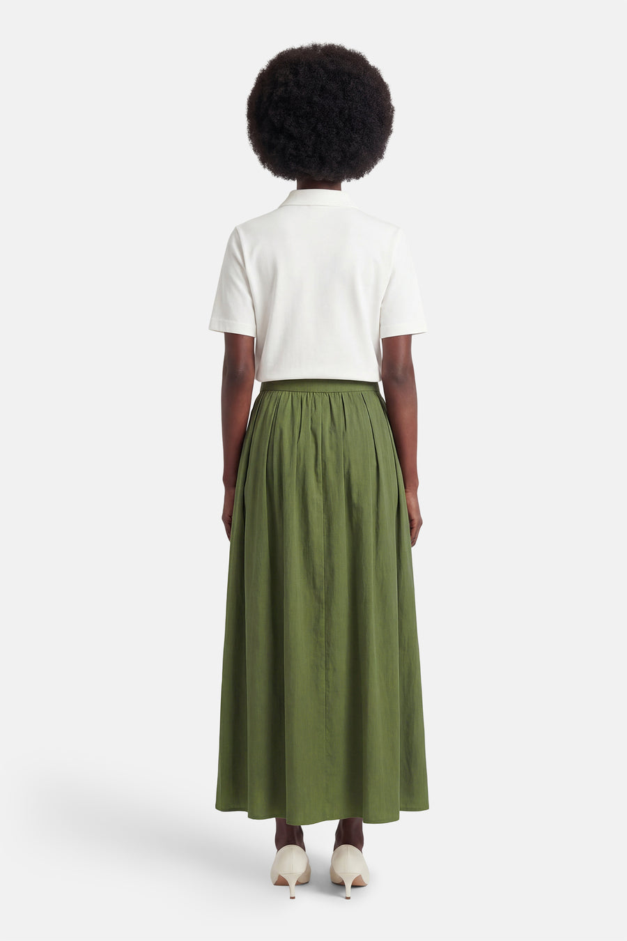 Jupe verte de ONLY, avec des plis et une silhouette trapèze, combinée avec un haut blanc et des talons beiges.