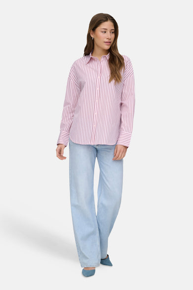 Roze hemd met lange mouwen van ONLY, gestreept, gecombineerd met wijde jeans en blauwe schoenen.