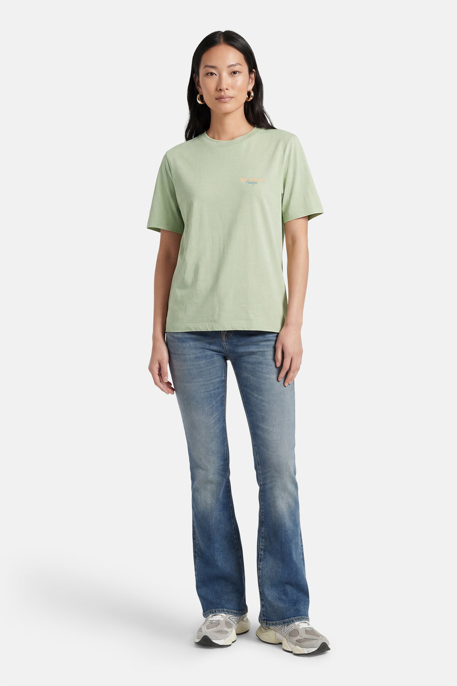 T-shirt vert à manches courtes ONLY®, avec un petit imprimé texte, porté avec un jean et des baskets.