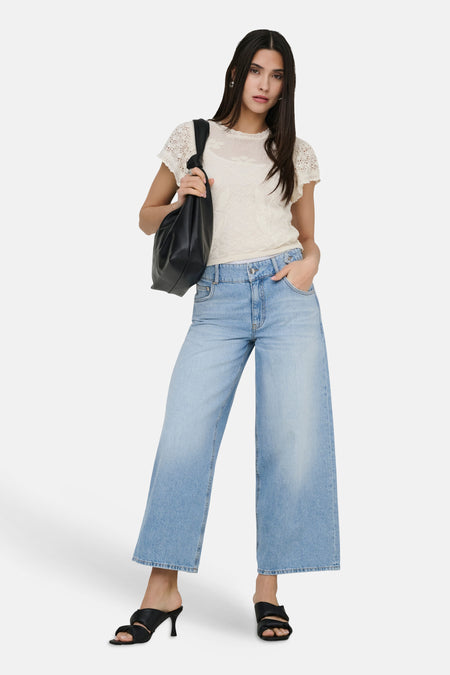 Wijde jeans van lichtblauw denim van ONLY, met brede pijpen en gedragen met een gebreide top en zwarte sandalen.
