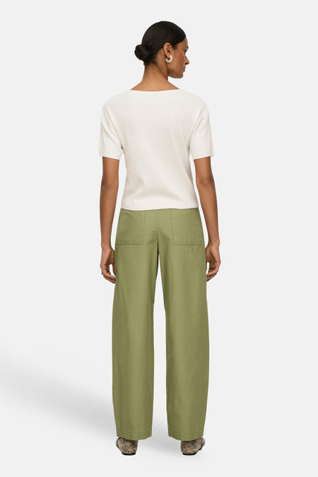 Groene broek van JDY met wijde pijpen en achterzakken, gecombineerd met een crèmekleurige top en opvallende schoenen.