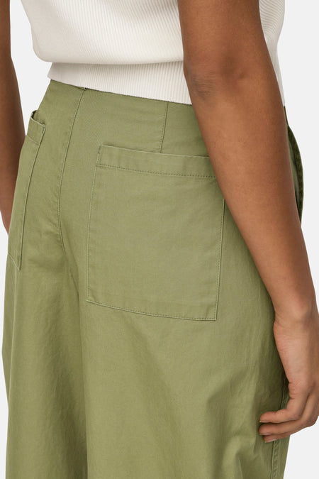 Groene broek van JDY met achterzakken, gedragen met een witte top en een neutrale achtergrond.
