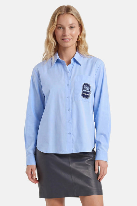 Blauw hemd met lange mouwen van JDY, met sardine-opdruk op de borstzak, gedragen door een model boven een donkere leren rok.