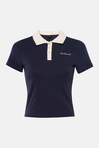 Polo bleu à manches courtes de ONLY, avec col blanc et broderie "Anchored". Le polo est associé à un jean.